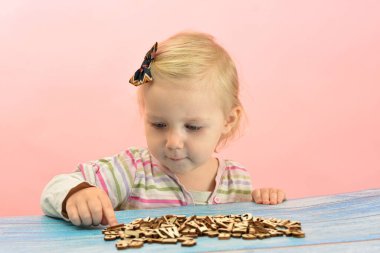 Çocuk masada gri harflerle oynuyor..