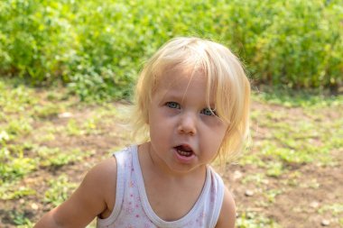 Çocuk bahçenin yanında durur ve yüzünü buruşturur..