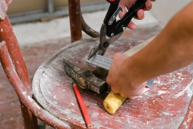 Metal makas kullanarak genç, sandalyede küçük bir alçıpan profili oluşturdu..