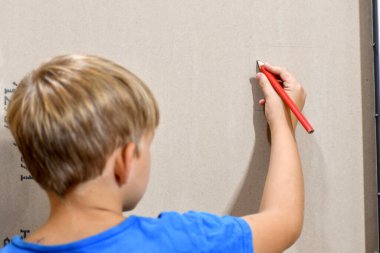 Çocuk evdeki alçıpana bir şey çiziyor..