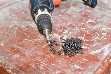 Sandalyenin üzerinde bir tornavida var ve bir sürü kendini beceren vida var..