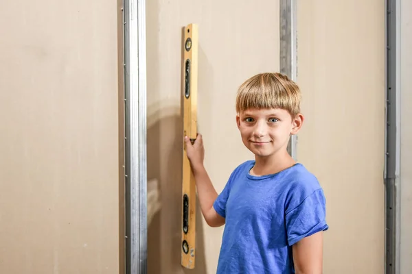 Gülümseyen Bir Çocuk Alçıpanın Yanında Bina Seviyesini Tutuyor — Stok fotoğraf
