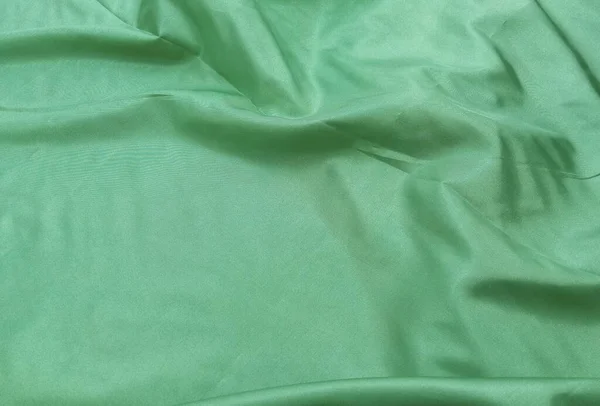 Açık yeşil saten kumaş, pürüzsüz ve parlak, buruşuk ve buruşuk yüzey