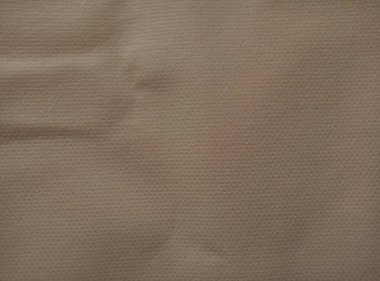 Buruşmuş koyu bej polipropilen kumaş lifleri. Dokumasız kumaş