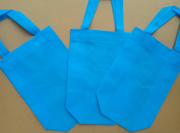 three light blue tote bags on a pastel beige background. bags made of polypropylene. spun tie bag