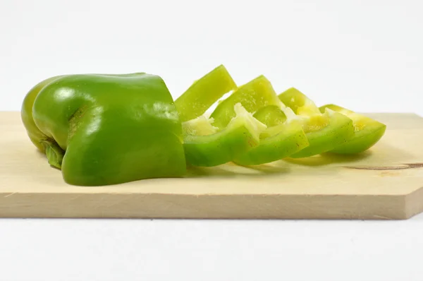 Green pepper sliced on wooden chopping board — Stock Photo, Image