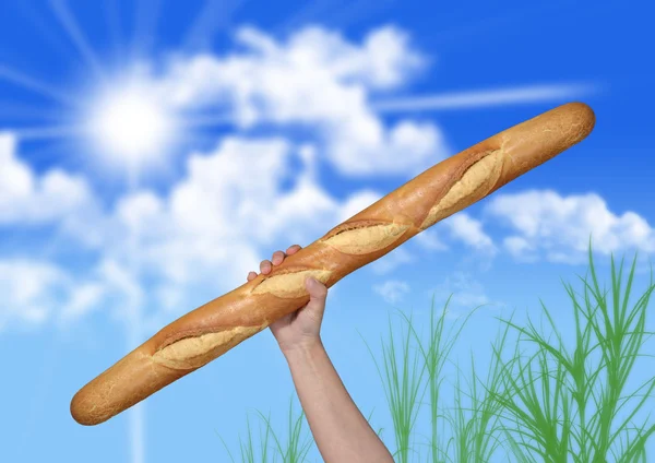 Pão com a mão sobre fundo desfocado — Fotografia de Stock