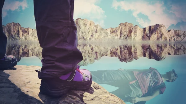 Persona de pie sobre rocas con reflejo en el agua — Foto de Stock