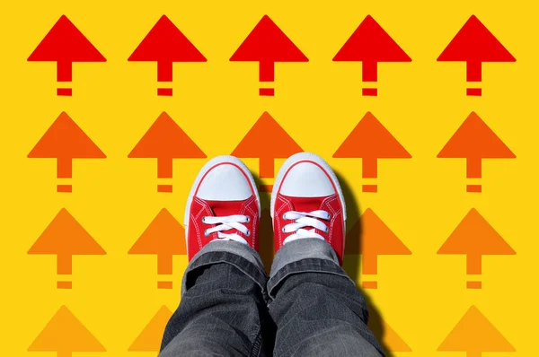 Röda sneakers på röda riktningspilar — Stockfoto