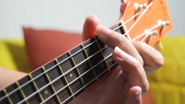 Person playing orange ukulele — Stock Video