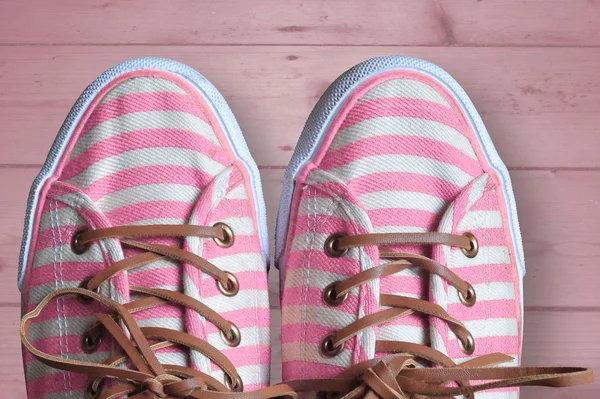 Fondo de madera rosa con zapatos con rayas rosas y blancas — Foto de Stock