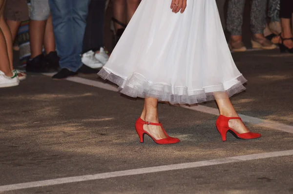 elderly woman dancing with red shoes and white dress