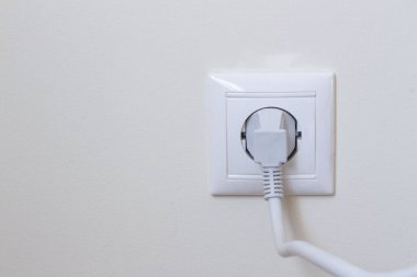 Beyaz kablo kablosu Avrupa 'nın duvar prizine bağlandı beyaz alçı duvarda kopyalama alanı ile
