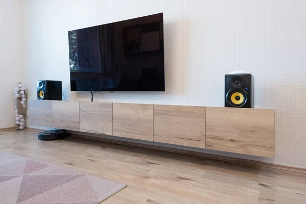 Cabinet and TV with speakers in living room of modern apartment
