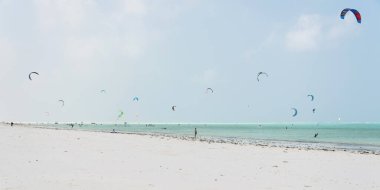 PAJE, ZANZIBAR - 23 DEC 2017: Uçurtmacılar Paje, Zanzibar 'da turkuaz mavi deniz ile beyaz kumlu sahilde kayak yapıyorlar