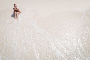 Beyaz bir kumsalda, Zanzibar 'da genç ve çekici bir kadının hava manzarası.