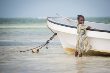 KIWENGWA, ZANZIBAR - 27 DEC 2017: Kiwengwa Köyü, Zanzibar 'da balıkçı teknesinde oynayan genç bir çocuk
