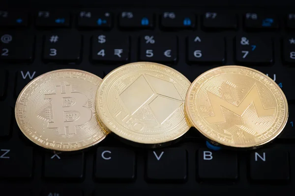 3つの黄金の暗号通貨コイン ラップトップの黒いキーボードのBitcoin Neo Monero — ストック写真