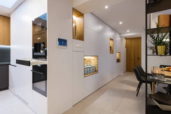 Beyaz ahşap bir dolap. İçinde ev aletleri ve raflar var. Modern evin içi.