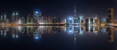 Business Bay 'in panoramik görüntüsü gece suda yansıyor, Dubai, BAE