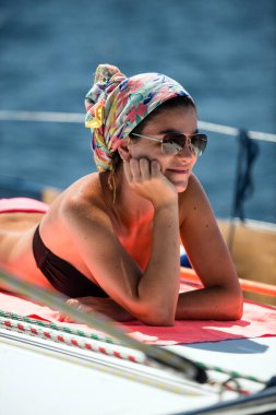 Young woman sunbathing on a deck of sailing yacht