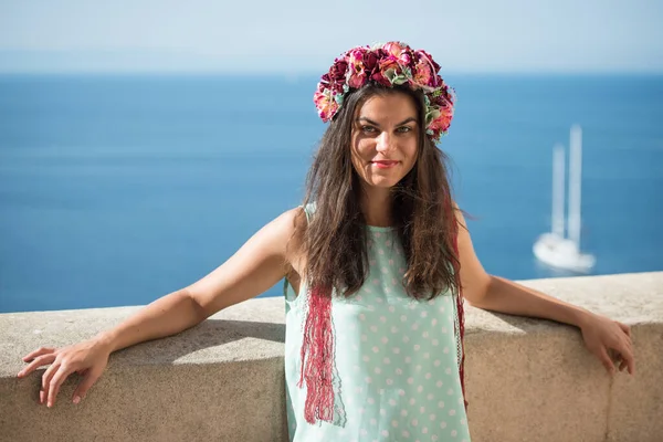 Young woman in blue shirt with flower head band, beautiful sea view in background