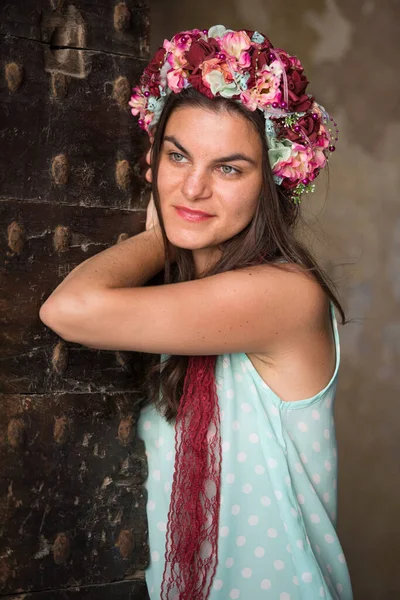 Young woman in blue shirt with flower head band standing by the door