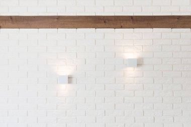 Beyaz tuğla duvar, iki ışık ve ahşap kiriş.