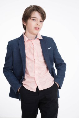 Beyaz arka planda poz veren takım elbiseli genç mutlu çocuk.