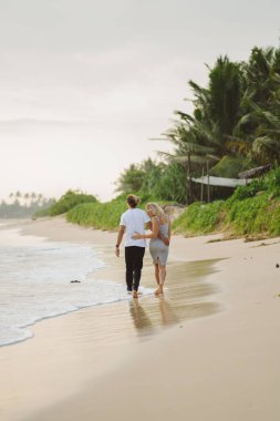 Sahilde kucaklaşan, gülümseyen güzel bir çift. Sevgililer Günü Tatilde.