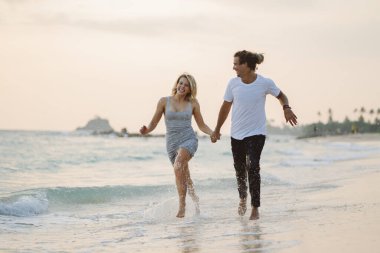 Sahilde kucaklaşan, gülümseyen güzel bir çift. Sevgililer Günü Tatilde.