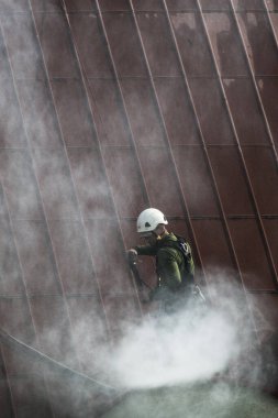 Çatıları basınçlı suyla yıkayan bir adam. Yükseklerde çalışan bir işçinin temizlik hizmetleri koruması