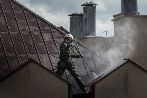 Ein Mann Wäscht Luftiger Höhe Ein Dach Mit Druckwasser Schutz Stockfoto
