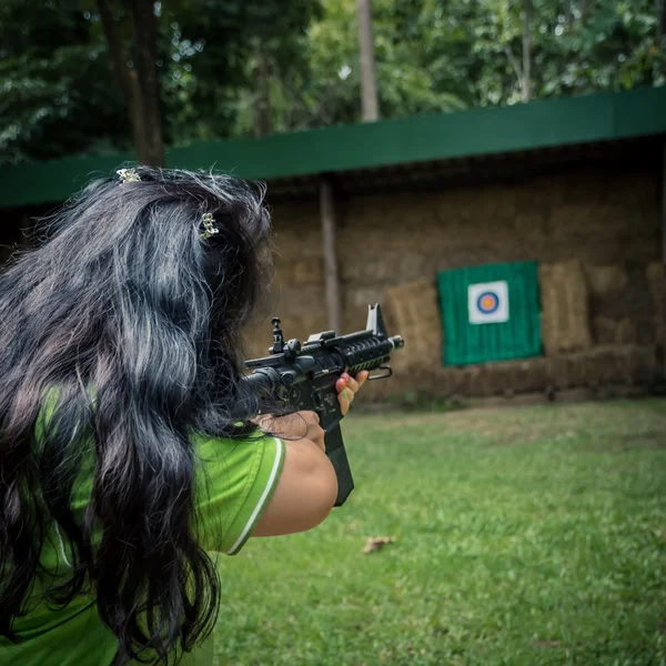 Uma jovem com uma arma apontando para um alvo — Fotografia de Stock