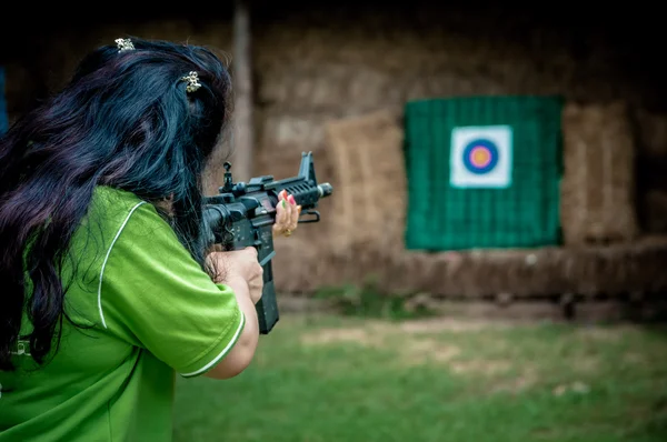 Une jeune fille avec une arme visant une cible — Photo