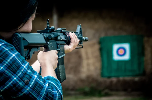 Uma jovem com uma arma apontando para um alvo — Fotografia de Stock