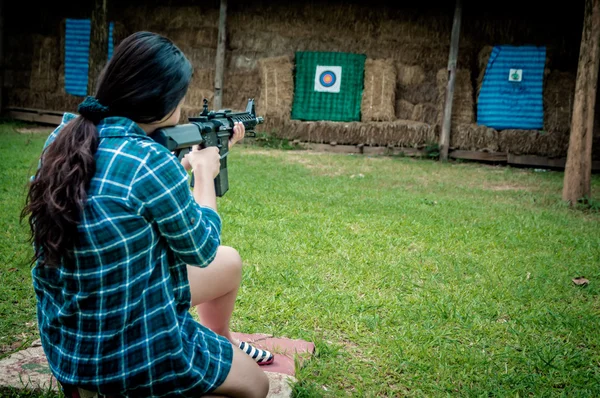 Une jeune fille avec une arme visant une cible — Photo