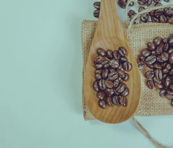 Kaffebönor och träsked på säck yta. Filtrera effekt retr — Stockfoto