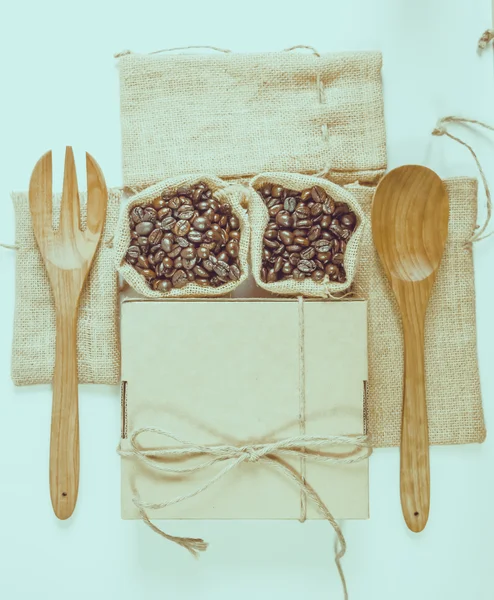 Ziarna kawy drewnianą łyżką i widelcem na powierzchni worek. Efekt filtra — Zdjęcie stockowe