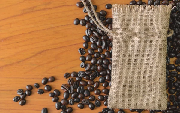 Saco y granos de café en la vieja mesa de madera . — Foto de Stock