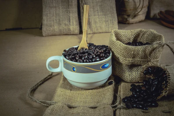 Vintage cup palonych ziaren kawy na worek powierzchni, nieostrość. — Zdjęcie stockowe