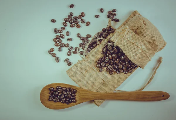 Kaffebönor och träsked på säck yta. — Stockfoto