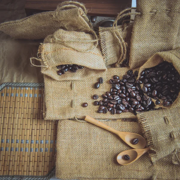 Foto vintage di chicchi di caffè e cucchiaio di legno sulla superficie del sacco . — Foto Stock
