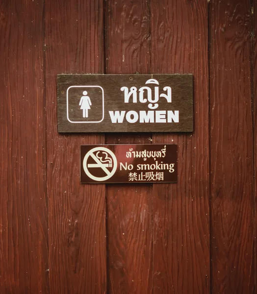 Жіночі туалетні знаки І ніяких знаків куріння на дерев'яних стінах . — стокове фото