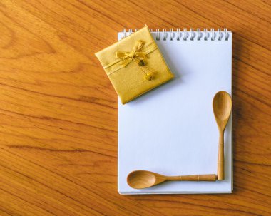 Altın şerit yay ve tahta kaşık boş not defteri üzerinde.