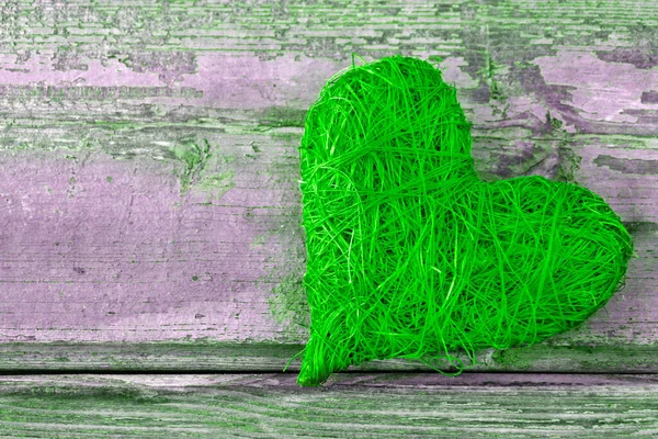 Green heart against a wooden background