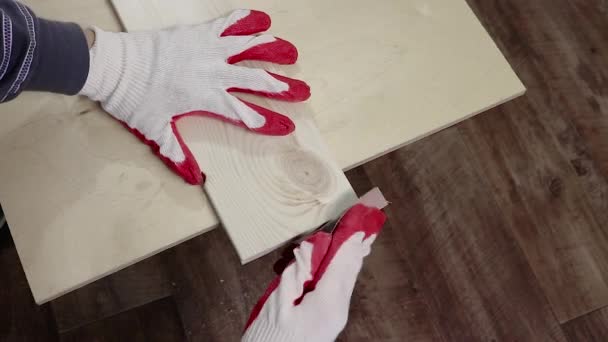 Broušení okrajů dřevěných borovicových prken pískovým papírem. Ruce v pracovních rukavicích zpracovávají dřevo, tesařské práce. — Stock video