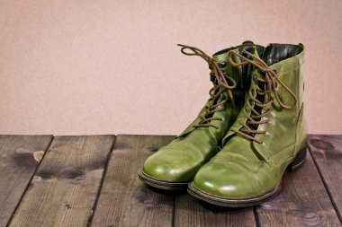 Ahşap döşeme tahtalarında hakiki yeşil deri çizmeler..