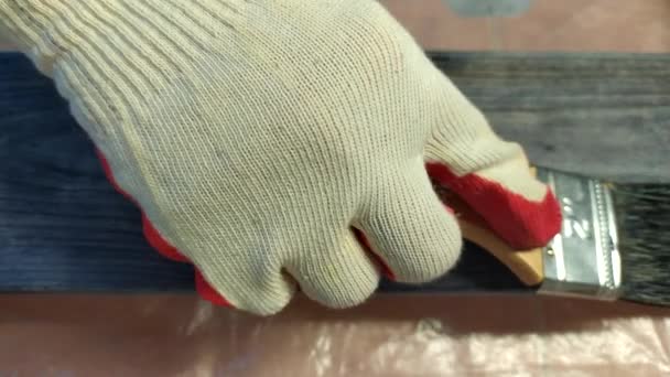 Eldivenli bir işçi, çam ağacından bir tahtayı ikinci kattaki fırçayla siyah bir lekeyle boyuyor. 4 bin. Boyama işi.. — Stok video