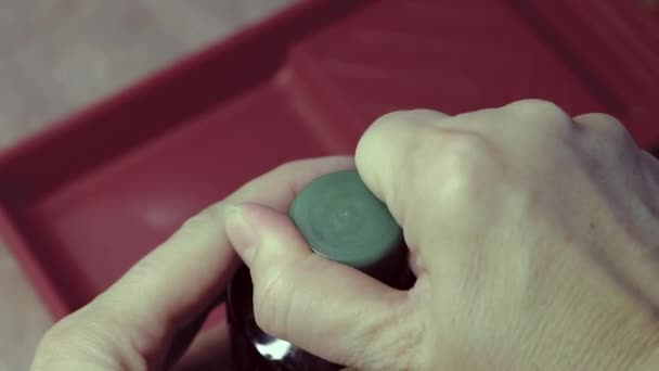 Le mani femminili aprono il tappo su una bottiglia macchiata, sullo sfondo di un vassoio di vernice. Opere di pittura. — Video Stock